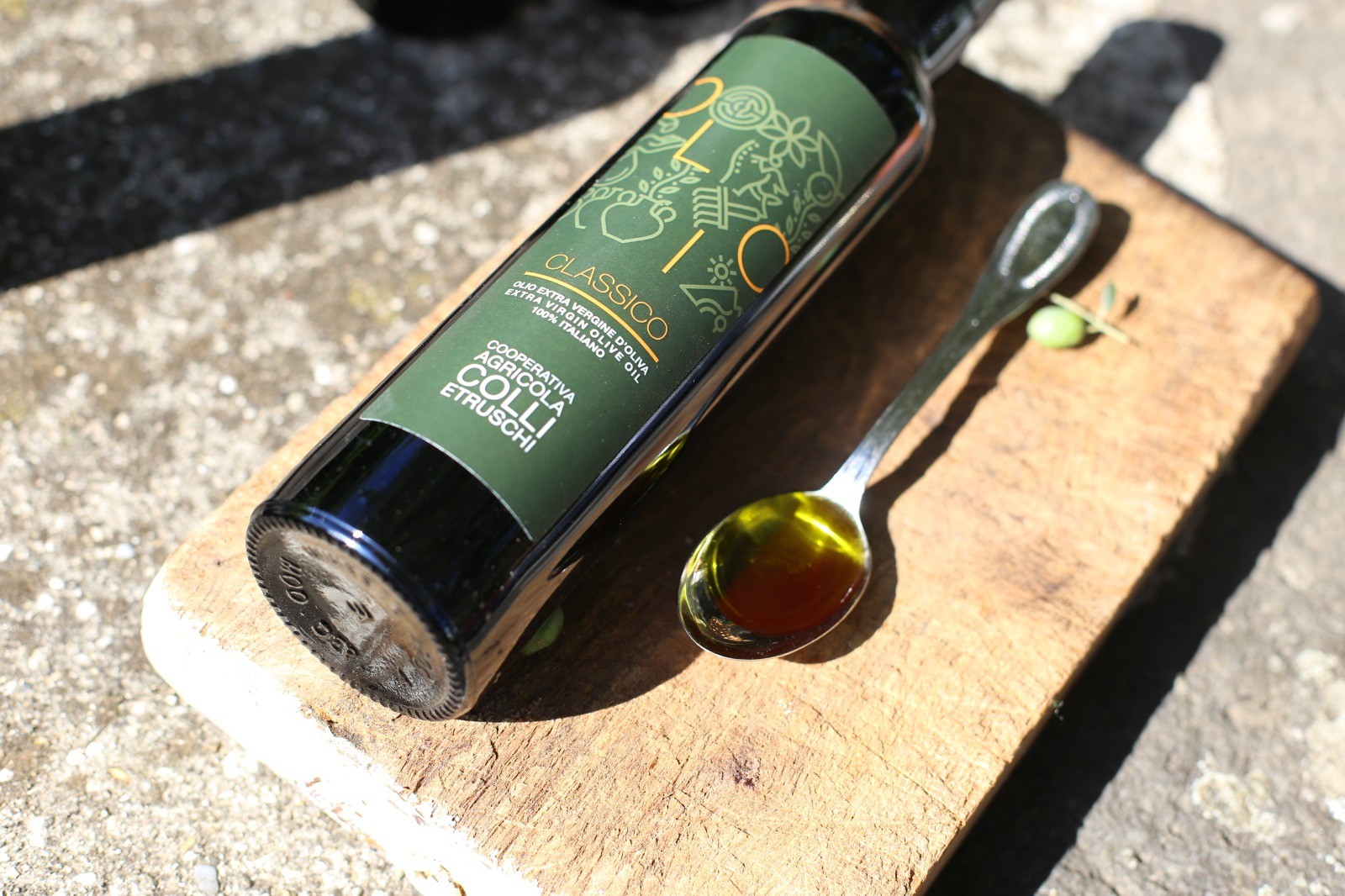 Bottiglia di olio d'oliva su tagliere con cucchiaio.