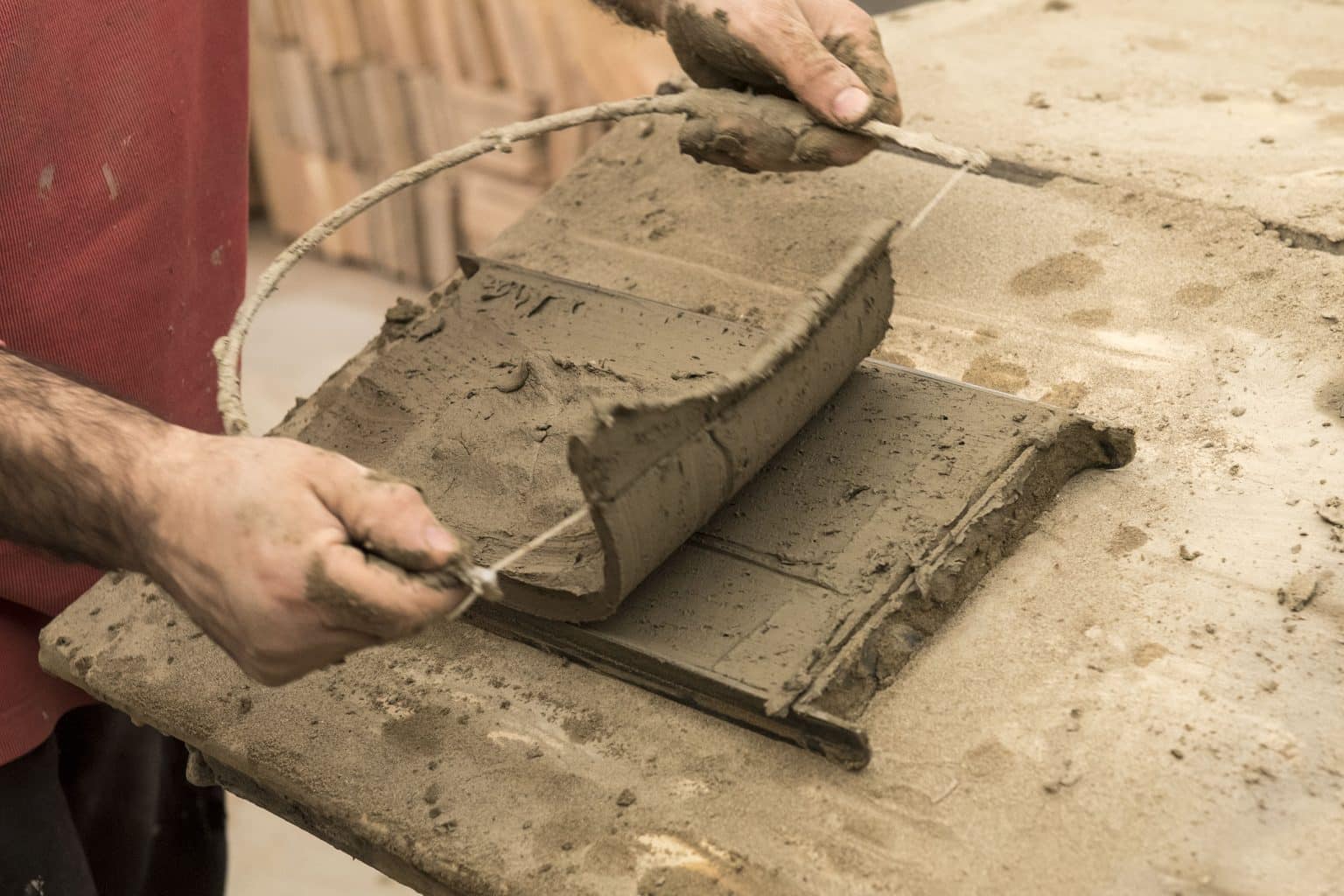 Mani che lavorano l'argilla su una superficie.