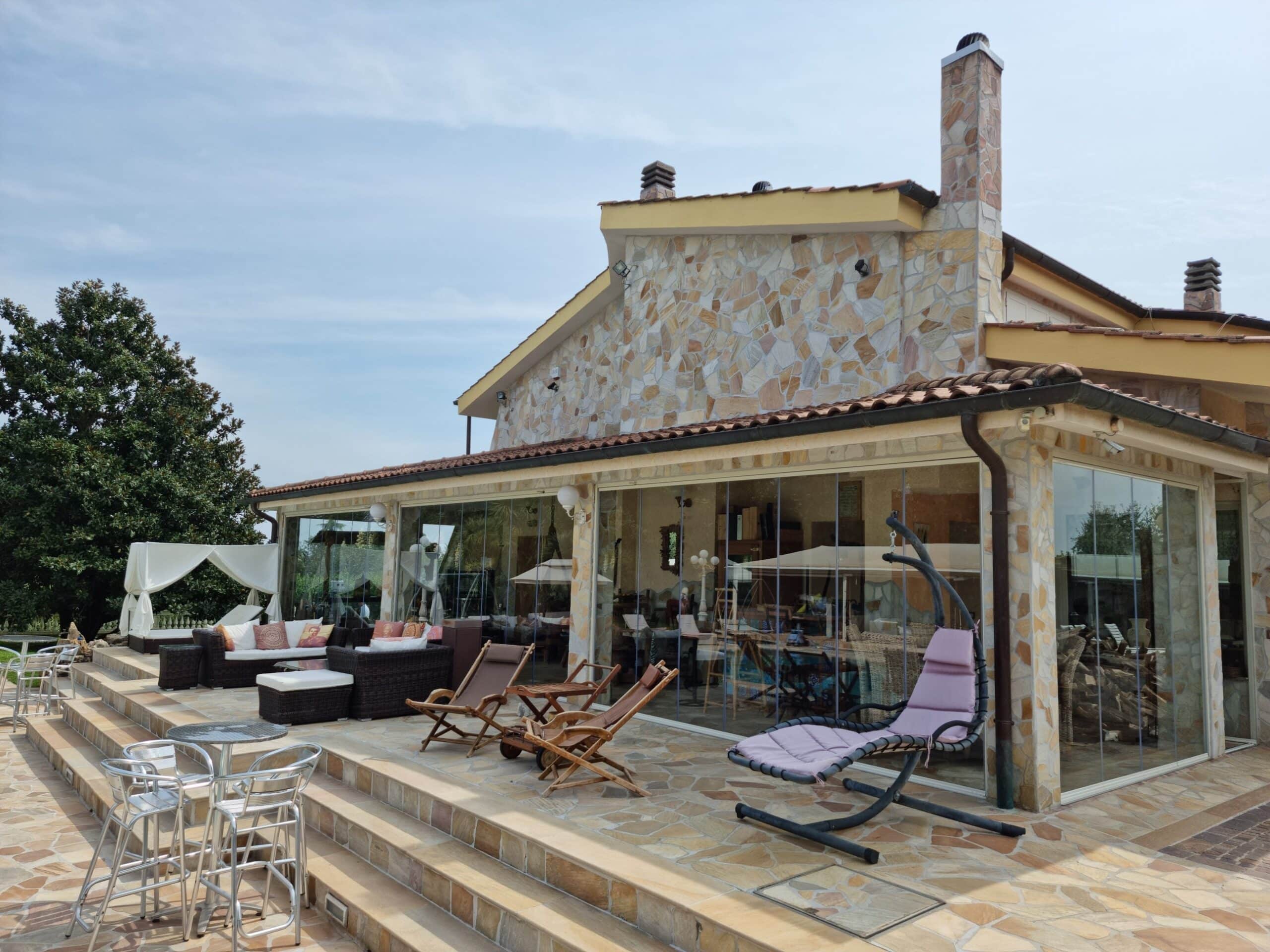 Terrazza con sedie e tavolini davanti a casa in pietra.