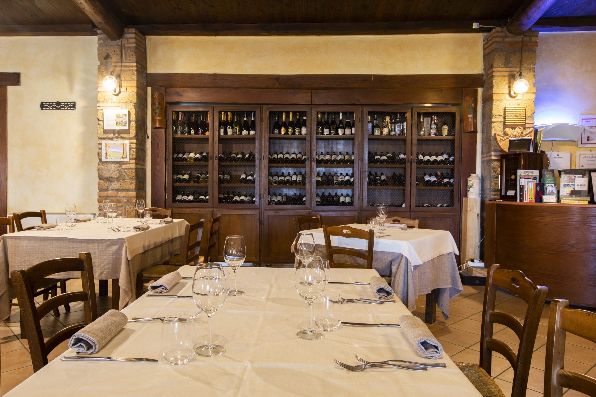 Ristorante con tavoli apparecchiati e scaffale di vini.