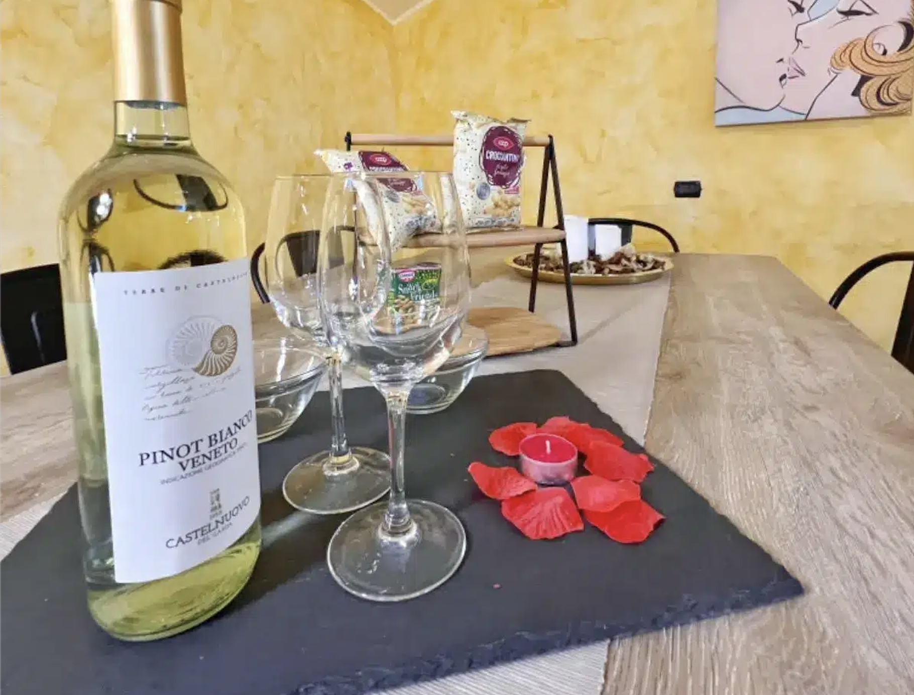 Bottiglia di vino, bicchieri e petali su tavolo.