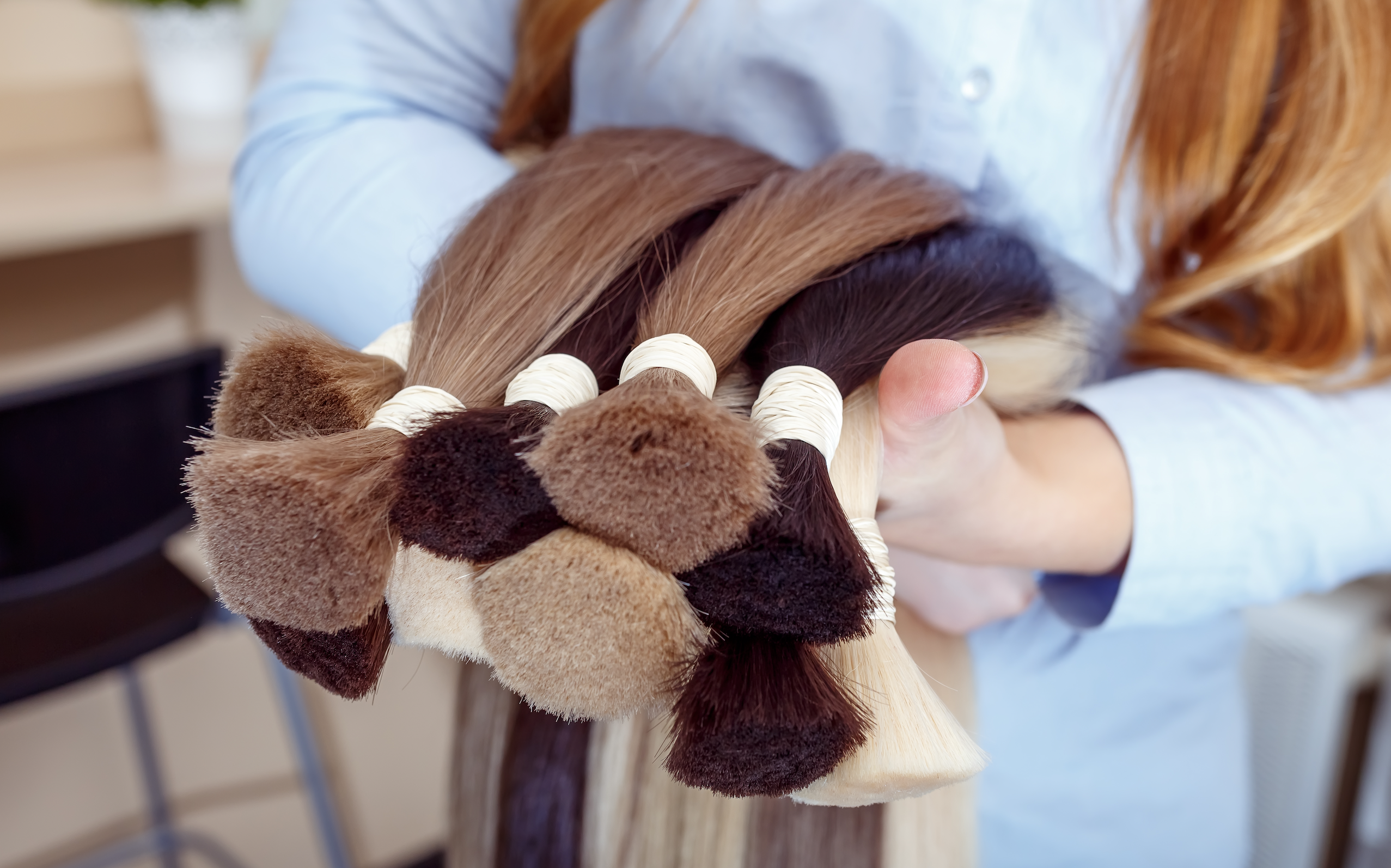 Ciocche di capelli di vari colori tenute in mano.
