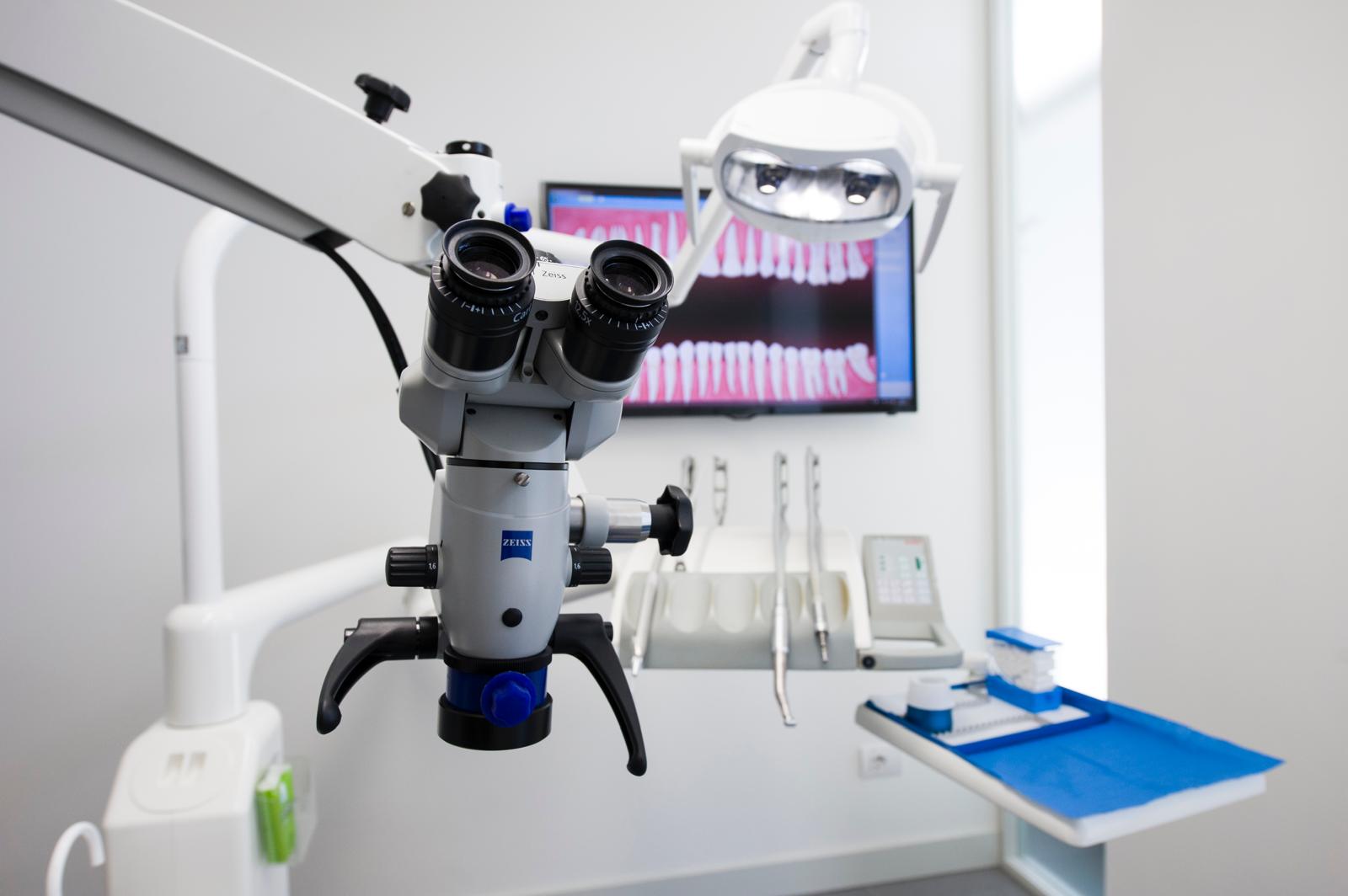 Microscopio in uno studio dentistico con strumenti e monitor.